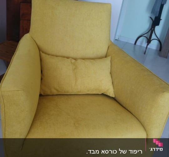 כורסה צהובה עם כרית תואמת על רצפה לבנה